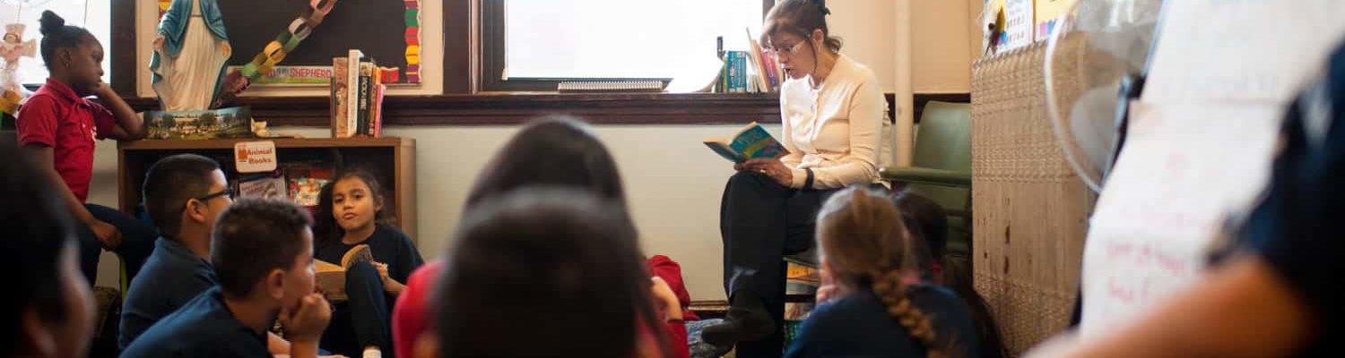 A teacher reading to students sitting on the floor
