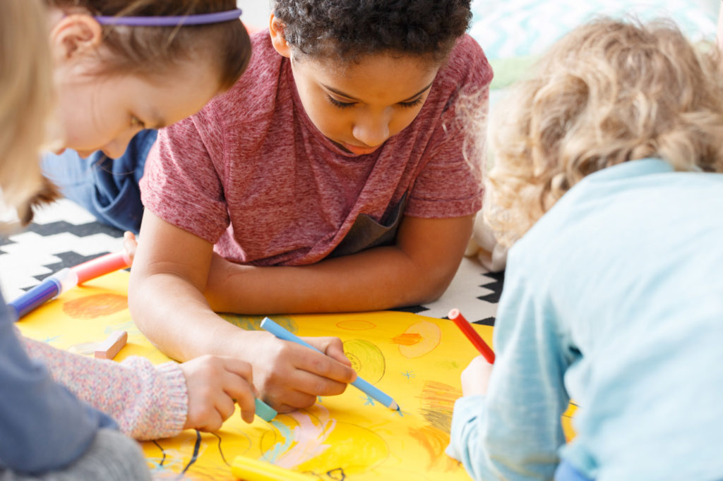 Young students coloring on yellow paper