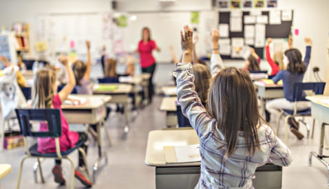 Students raising their hands in desks