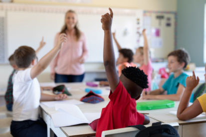 A group of students raising their hands in a classroom