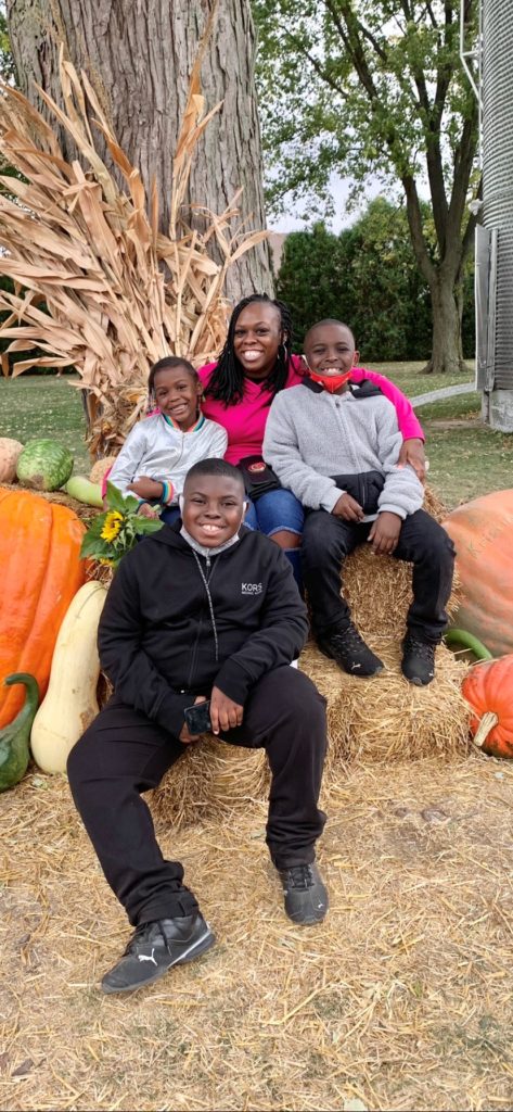 Family sitting on a hay bale with pumpkins