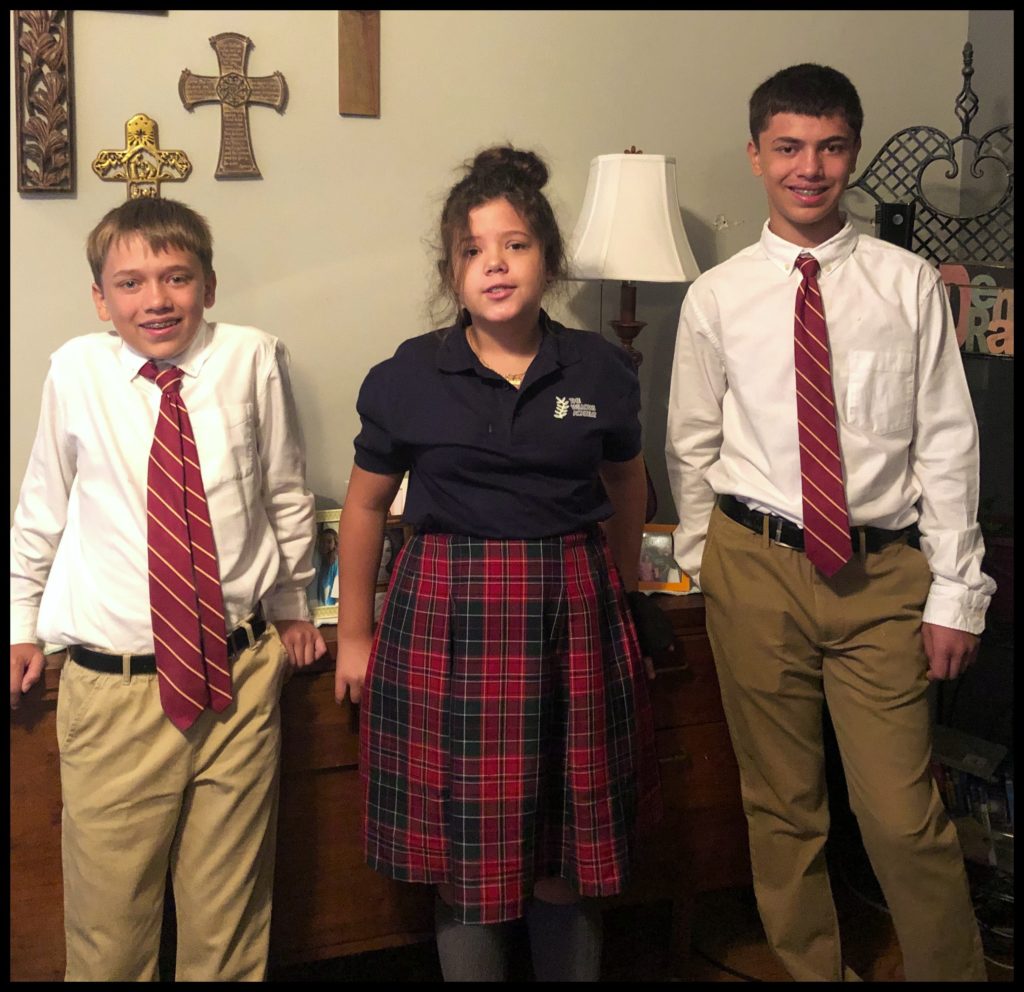 Three kids in school uniforms smiling